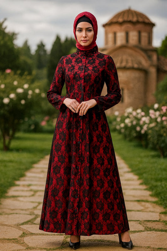 Woman in a red and black patterned dress standing on a stone path with greenery and a building in the background.