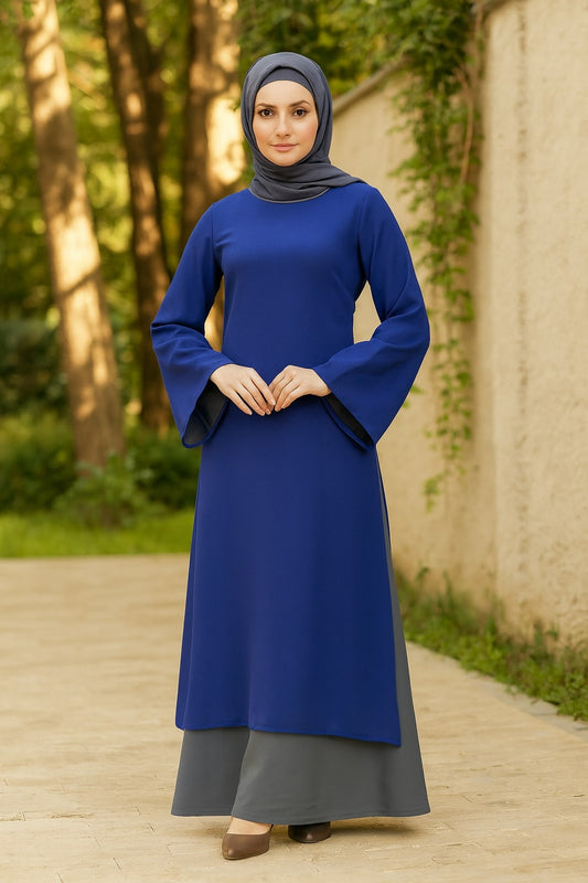 Woman wearing a blue dress and gray hijab standing outdoors.