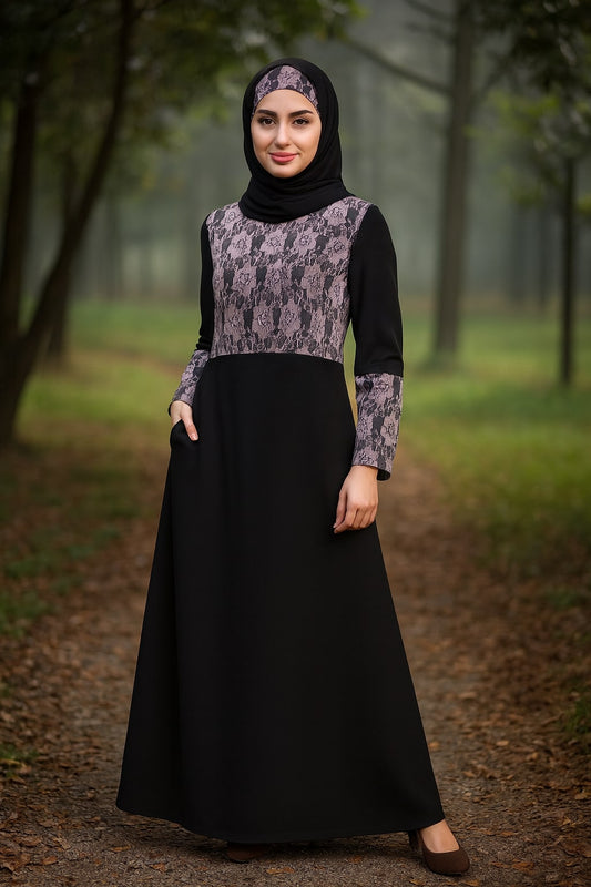 Woman wearing a black hijab and a black and patterned top with a long black skirt in a forest setting.