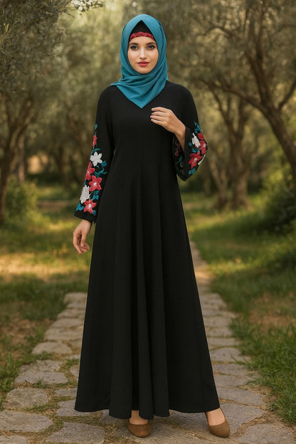 Woman wearing a black dress with colorful sleeves and a teal hijab in a forest setting
