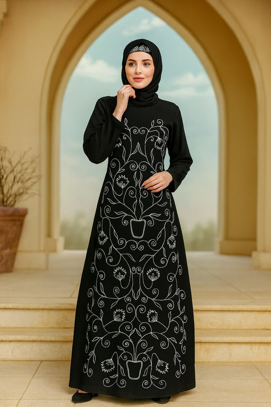 Woman wearing a black abaya with white embroidery in front of an archway.