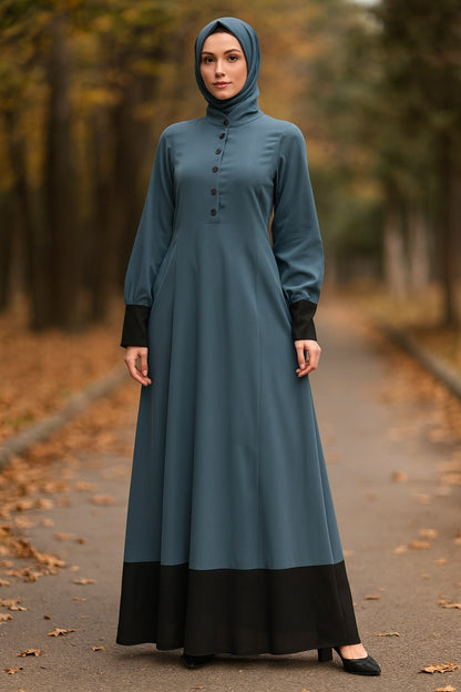 Woman wearing a teal dress with black bottom half on a path with blurred trees in the background