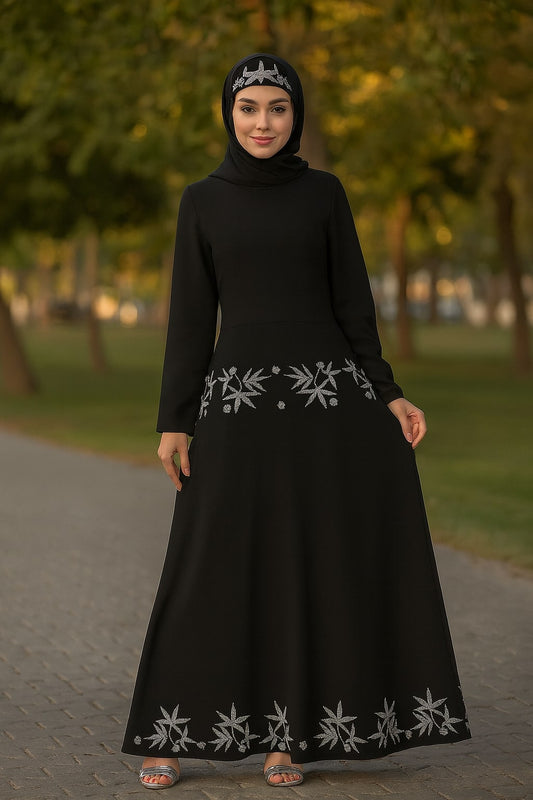 Woman wearing a black dress with white embroidery in an outdoor setting