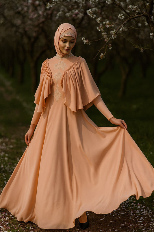 Woman in a peach dress and hijab standing in a natural setting with trees and grass.