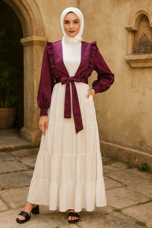 Woman wearing a white dress with a purple cardigan in an outdoor setting.