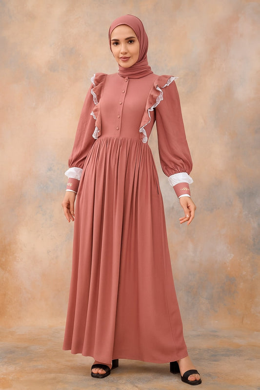 Woman wearing a long, light pink dress with ruffled sleeves against a warm-toned background