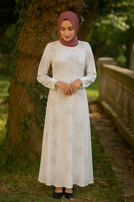 Woman in a white lace dress and hijab standing outdoors near a tree