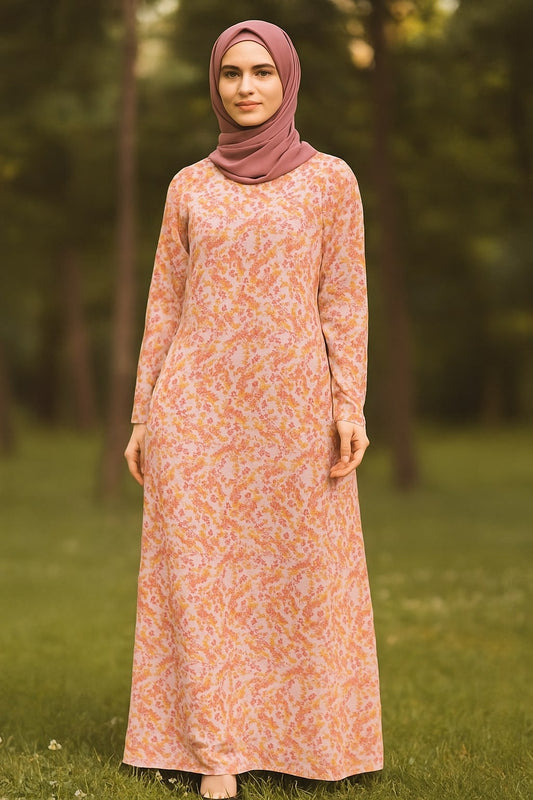 Woman wearing a patterned dress and hijab standing in a grassy area with trees.