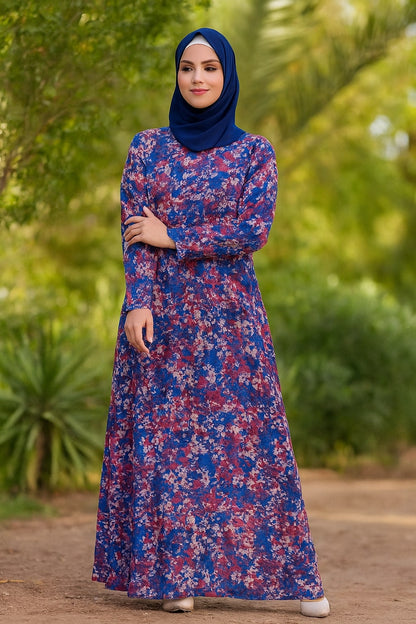 Woman wearing a blue and pink floral dress with a matching hijab in a natural setting.