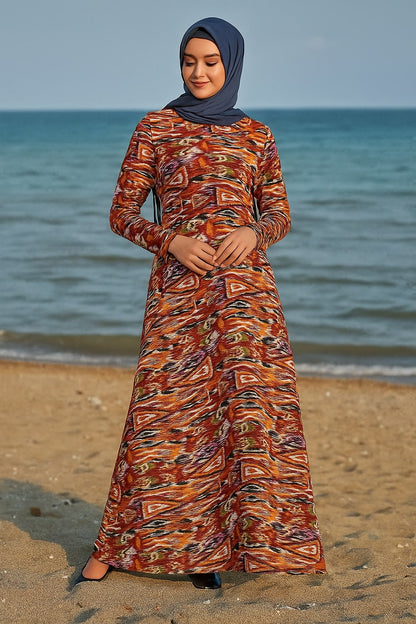 Woman in a patterned dress standing on a beach with ocean in the background
