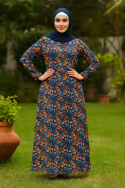Woman wearing a blue floral dress with orange flowers standing outdoors on grass.