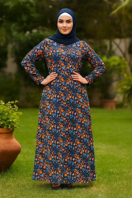 Woman wearing a blue floral dress with orange flowers standing outdoors on grass.
