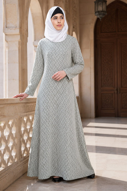 Woman wearing a long, patterned dress standing on a balcony with architectural background