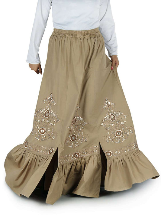 A khaki-colored, A-line skirt with embroidered detailing along the panels, featuring slits at the bottom and a gathered bottom skirt.