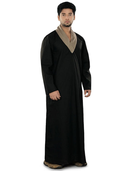 A man wearing a black galabiyya with a shawl collar neck and straight sleeves, featuring utility pockets on the sides.