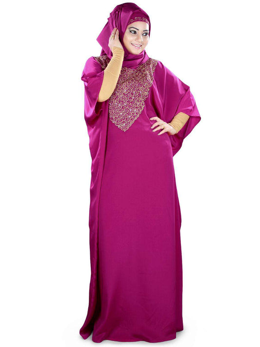 A woman wearing a pink traditional kaftan with floral embroidery and a round neckline.
